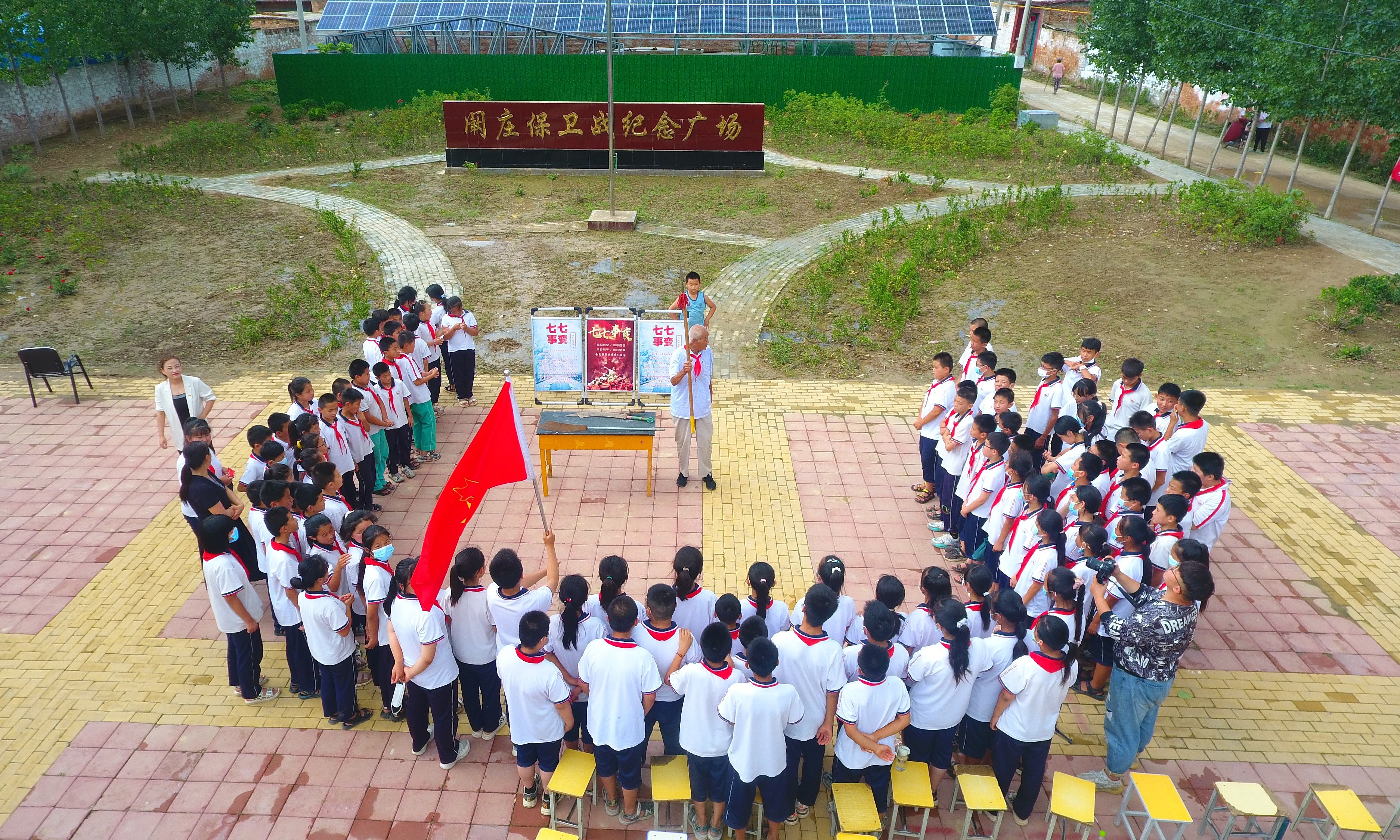 2022年7月6日，山東省聊城市，在茌平區(qū)菜屯鎮(zhèn)闞莊村的闞莊保衛(wèi)戰(zhàn)紀念廣場，闞莊保衛(wèi)戰(zhàn)親歷者王光木老人，為小學(xué)生們講述抗戰(zhàn)故事，展示大刀、長矛。