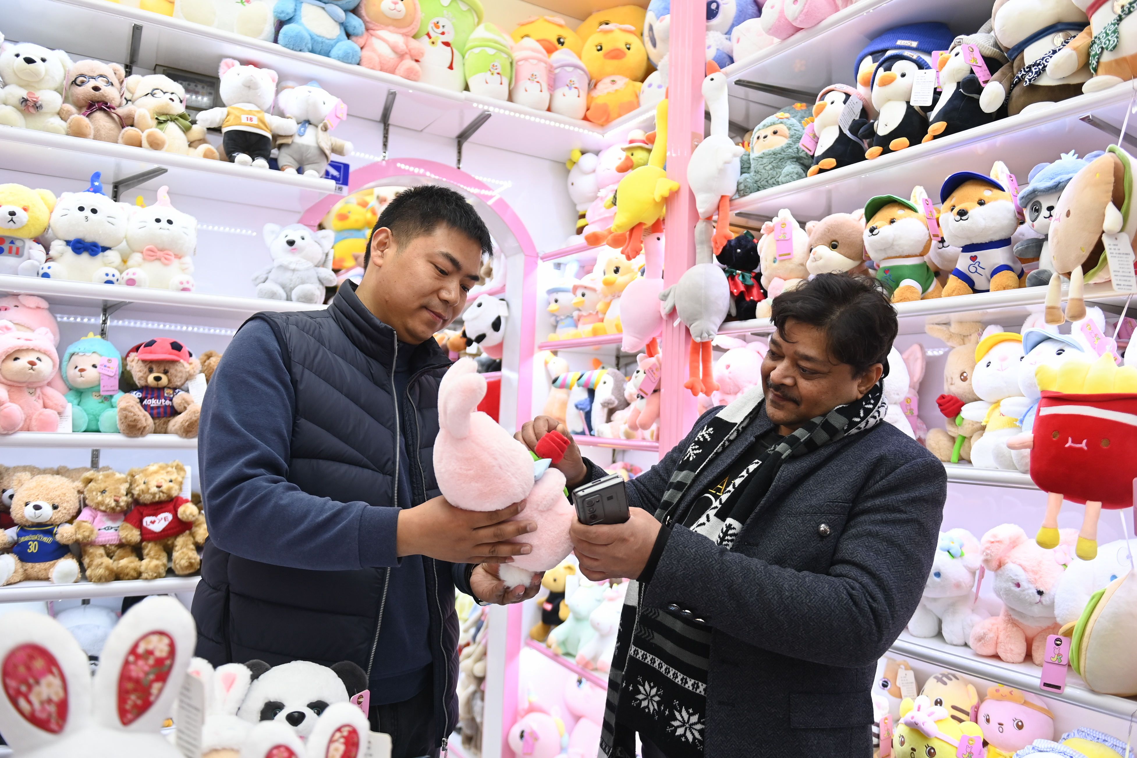 2023年2月2日，來自印度的客商（右）在義烏國際商貿(mào)城的一家玩具店鋪內(nèi)選購。