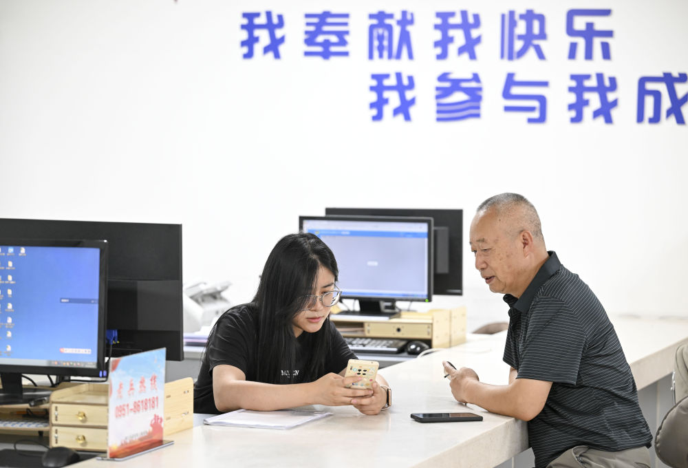 2024年6月20日，在寧夏銀川市金鳳區(qū)長城花園社區(qū)黨群服務中心，工作人員幫助居民辦理業(yè)務。圖片來源 新華社